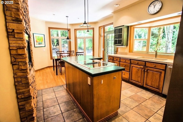 kitchen featuring a sink, black electric cooktop, a center island, light tile patterned floors, and brown cabinets