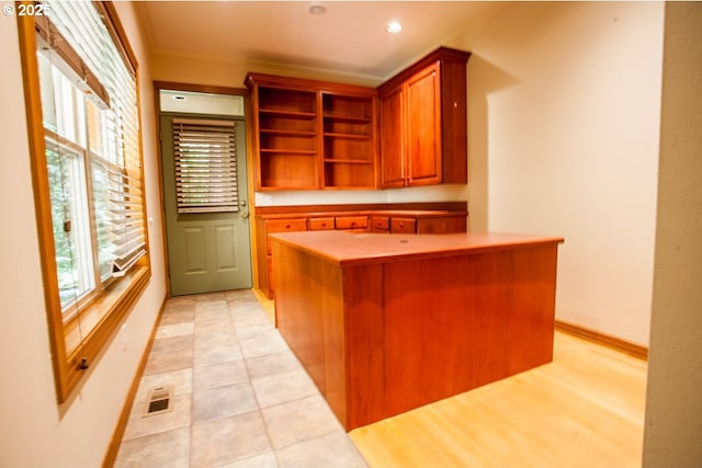 kitchen featuring a kitchen island, open shelves, baseboards, brown cabinetry, and recessed lighting