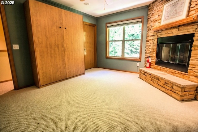 unfurnished living room featuring carpet flooring, a fireplace, ceiling fan, baseboards, and ornamental molding