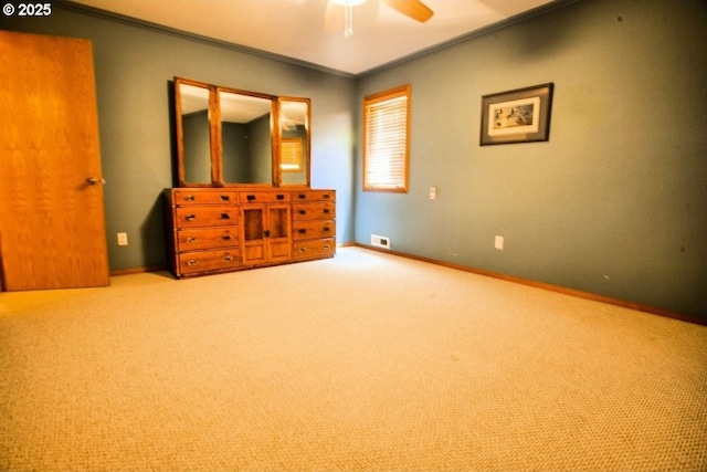 unfurnished bedroom with crown molding, carpet flooring, baseboards, and ceiling fan