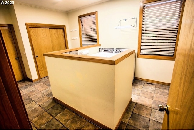 kitchen with crown molding, baseboards, and a peninsula