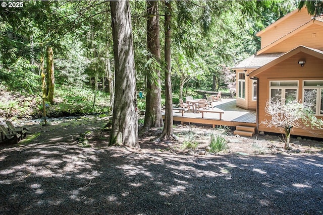 view of yard with a deck and a view of trees