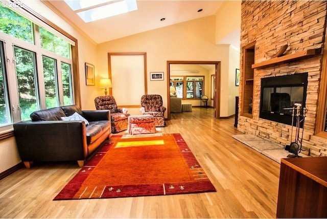 living area with wood finished floors, a skylight, a fireplace, high vaulted ceiling, and baseboards