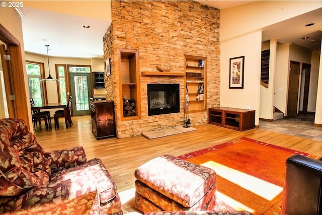 living area with wood finished floors, built in shelves, and a fireplace