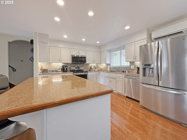 kitchen with a sink, tasteful backsplash, appliances with stainless steel finishes, and white cabinetry