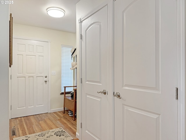 hallway with light wood-style flooring, baseboards, and visible vents