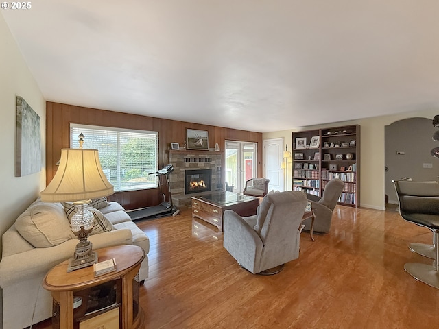 living area featuring a glass covered fireplace, wood finished floors, and wood walls