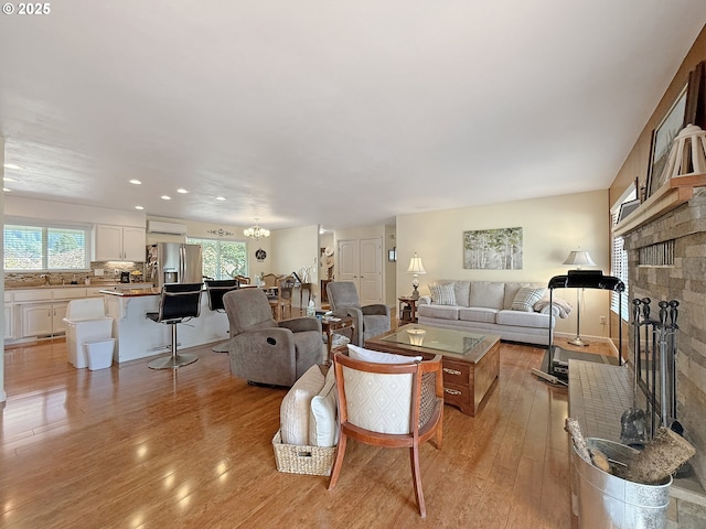 living area with a chandelier, recessed lighting, a fireplace, and light wood-type flooring