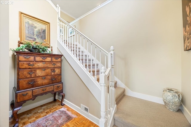 staircase featuring visible vents, baseboards, and ornamental molding