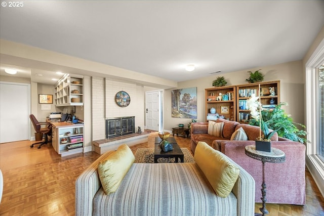 living area featuring visible vents, a brick fireplace, and baseboards