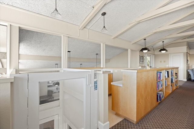 kitchen featuring a textured ceiling, vaulted ceiling with beams, carpet floors, and pendant lighting