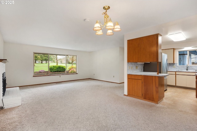 kitchen with light countertops, light colored carpet, open floor plan, and a fireplace with raised hearth