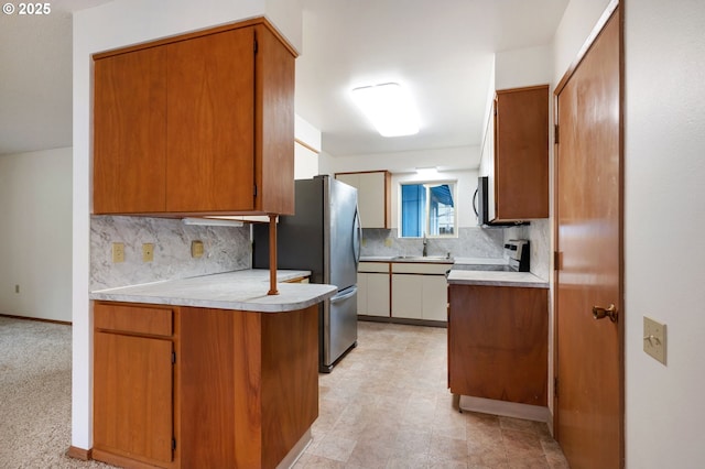 kitchen featuring stainless steel appliances, a peninsula, decorative backsplash, and light countertops