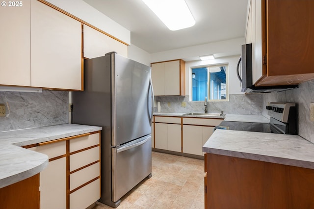 kitchen with tasteful backsplash, light floors, light countertops, appliances with stainless steel finishes, and a sink