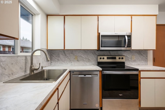 kitchen featuring backsplash, appliances with stainless steel finishes, light countertops, and a sink