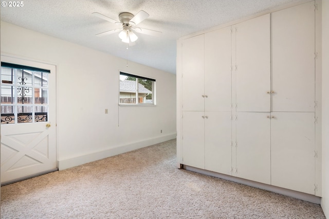 unfurnished bedroom featuring a closet, light colored carpet, a textured ceiling, and baseboards