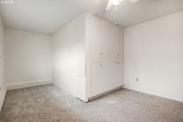 interior space featuring light carpet, a textured ceiling, and ceiling fan