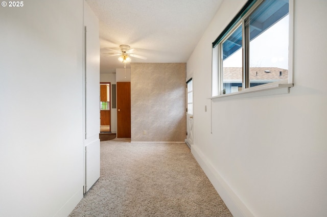 hallway with baseboards, a textured ceiling, and carpet