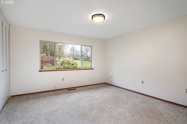 carpeted spare room with visible vents and baseboards