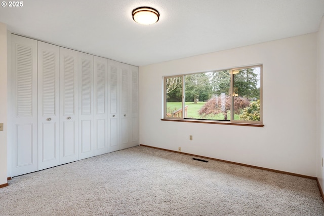 unfurnished bedroom with visible vents, baseboards, a closet, and carpet flooring