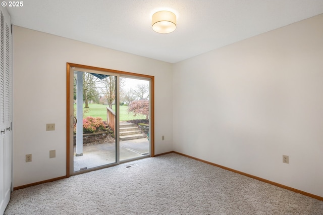 empty room with carpet, visible vents, and baseboards