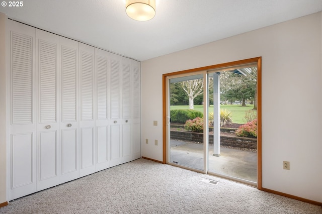 unfurnished bedroom featuring a closet, baseboards, access to exterior, and carpet flooring