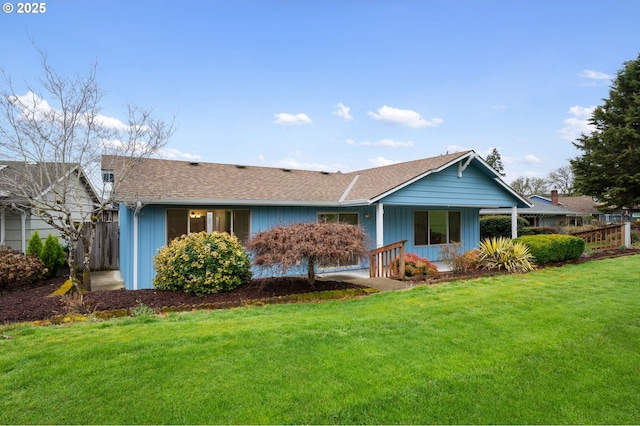 view of front of property featuring a front lawn, fence, and roof with shingles