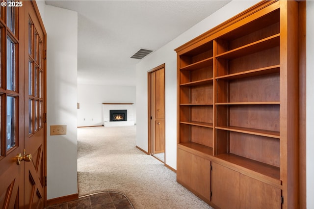 corridor featuring visible vents, carpet floors, and baseboards