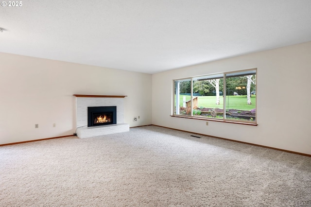 unfurnished living room with visible vents, a fireplace, baseboards, and carpet floors