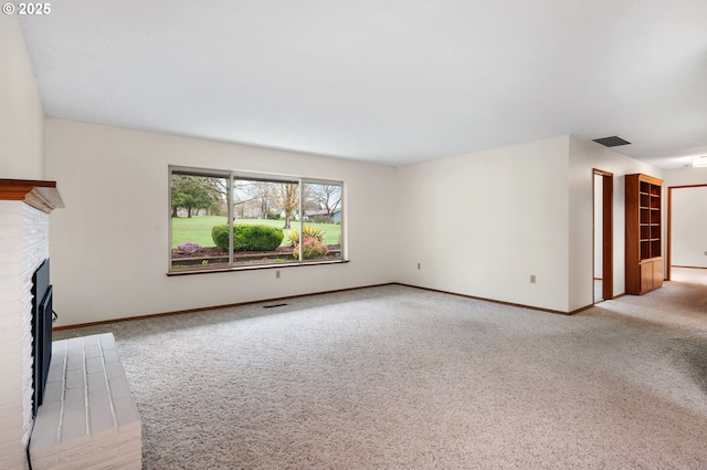 unfurnished living room with a fireplace, visible vents, carpet floors, and baseboards