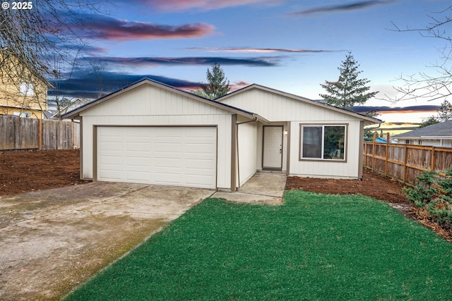 view of front of property featuring driveway, a garage, fence, and a front yard