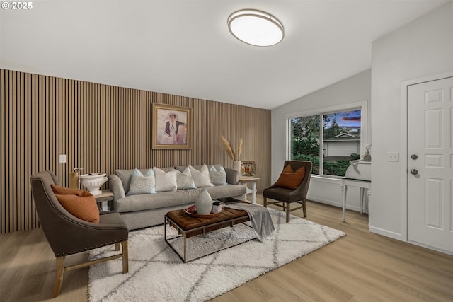 living area featuring vaulted ceiling, baseboards, and wood finished floors