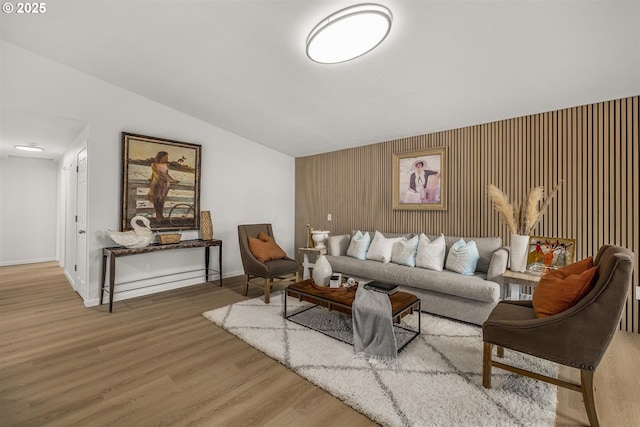 living area with lofted ceiling, baseboards, and wood finished floors