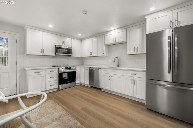 kitchen with light wood-style flooring, appliances with stainless steel finishes, light countertops, and a sink