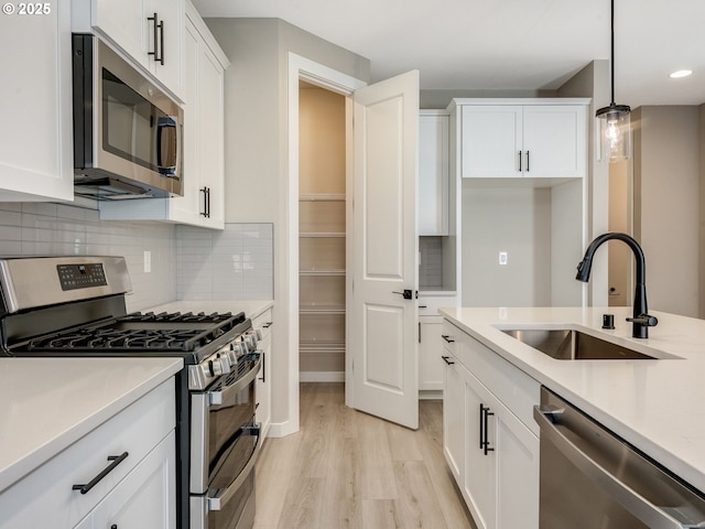702 NW 178th Way, Ridgefield, WA 98642 - kitchen with appliances with stainless steel finishes, a sink, light wood finished floors, light countertops, and white cabinets