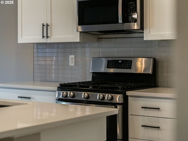 702 NW 178th Way, Ridgefield, WA 98642 - kitchen with stainless steel appliances, white cabinetry, tasteful backsplash, and light countertops