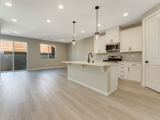 702 NW 178th Way, Ridgefield, WA 98642 - kitchen featuring appliances with stainless steel finishes, baseboards, light wood finished floors, light countertops, and a kitchen island with sink