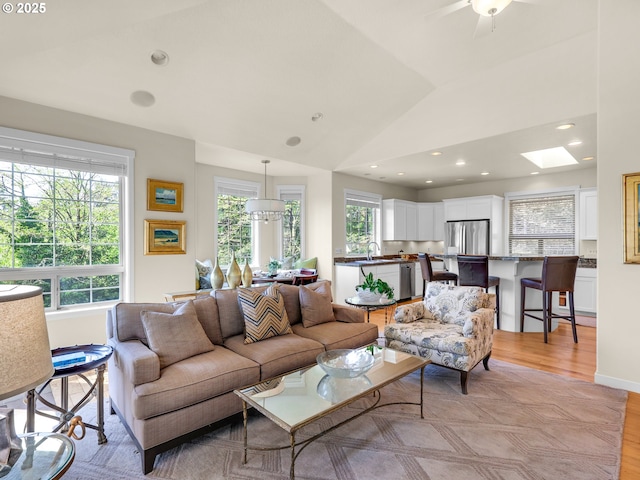 living room with light wood-style floors, recessed lighting, baseboards, and lofted ceiling with skylight