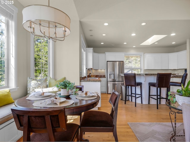dining area with recessed lighting, a notable chandelier, a skylight, and light wood-type flooring