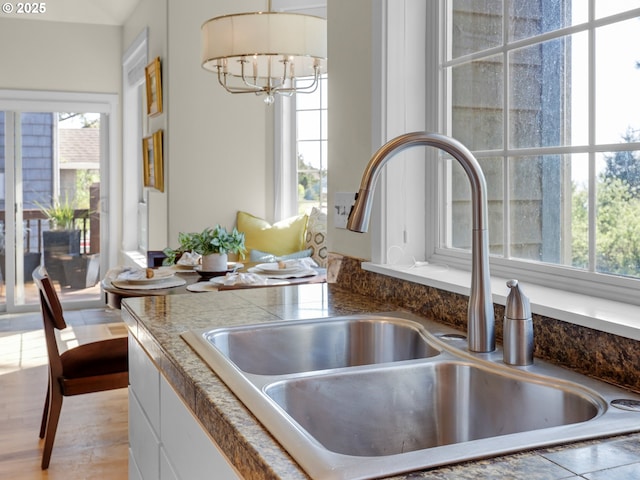 room details featuring a sink, white cabinetry, and a notable chandelier