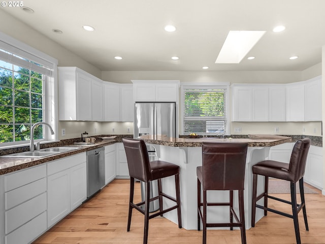 kitchen with a sink, appliances with stainless steel finishes, a kitchen bar, and white cabinetry