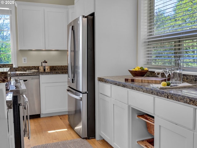 kitchen featuring white cabinets, stainless steel appliances, a healthy amount of sunlight, and light wood-type flooring
