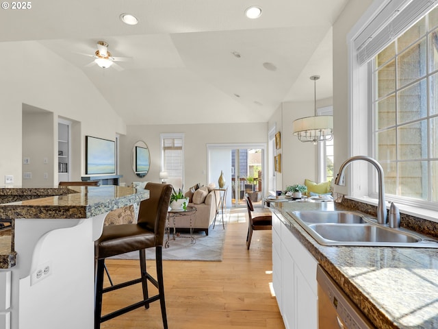 kitchen with a sink, light wood-style flooring, a breakfast bar area, and tile countertops