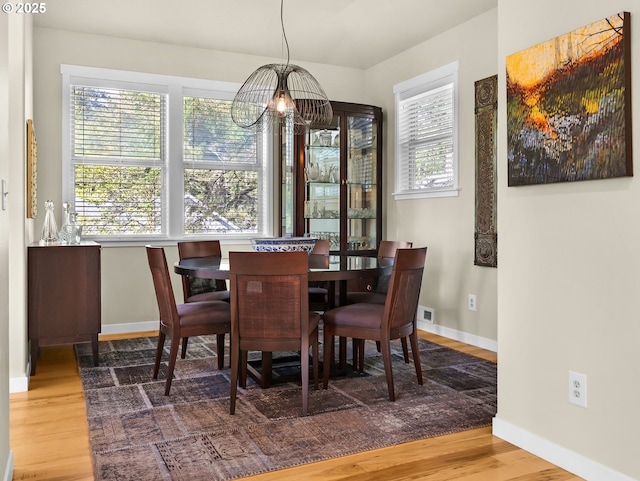 dining space featuring baseboards, wood finished floors, and a notable chandelier