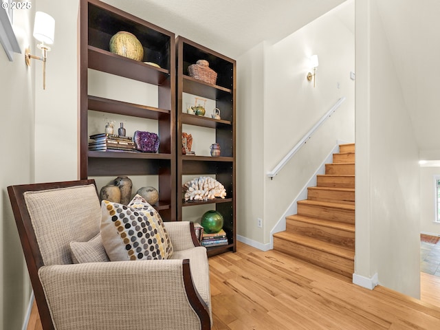 living area featuring baseboards, light wood finished floors, and stairway