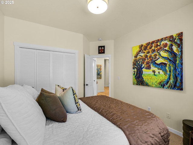 carpeted bedroom featuring baseboards and a closet
