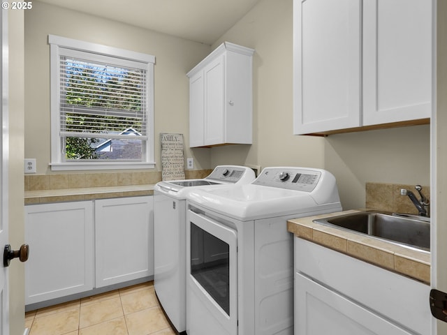 laundry area with a sink, light tile patterned floors, washing machine and dryer, and cabinet space