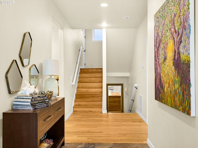 hall featuring baseboards, recessed lighting, wood finished floors, and stairway