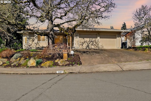 ranch-style house featuring an attached garage, driveway, and stucco siding