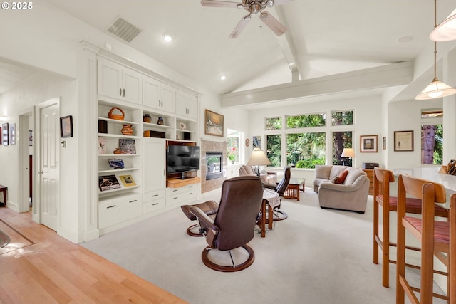 living area with visible vents, beam ceiling, plenty of natural light, and a tiled fireplace